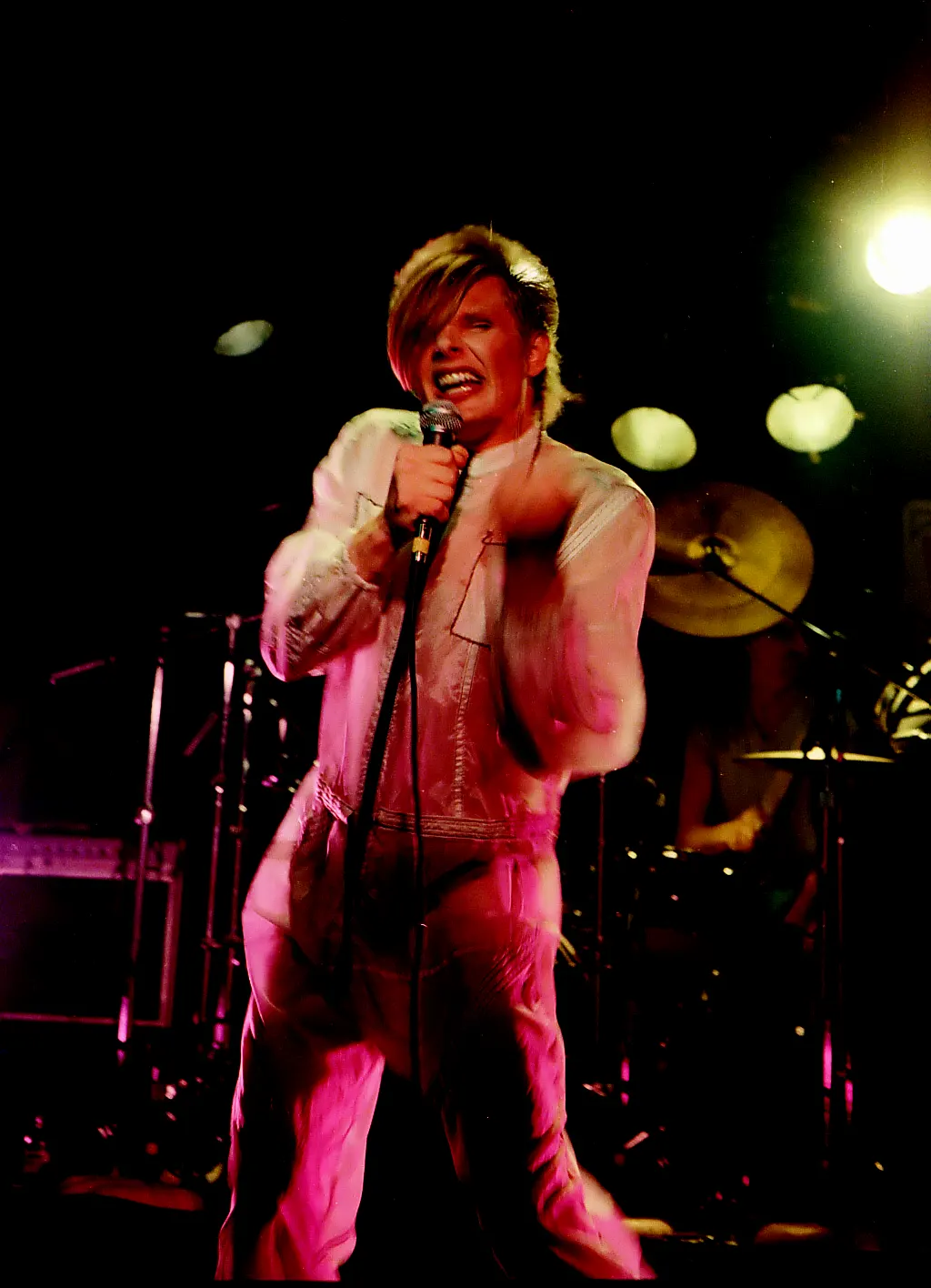 Robert Mitchell Patterson on stage singing with intense colours of stage lighting